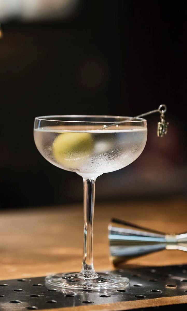 Ice cold Martini in vintage frosted glass with a green olive. A quintessential aperitif synonym of luxury and good times.