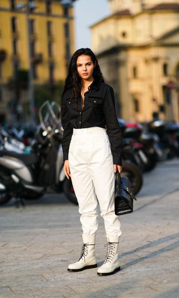 Doina Ciobanu con pantalones blancos, camisa negra y botas de cordones