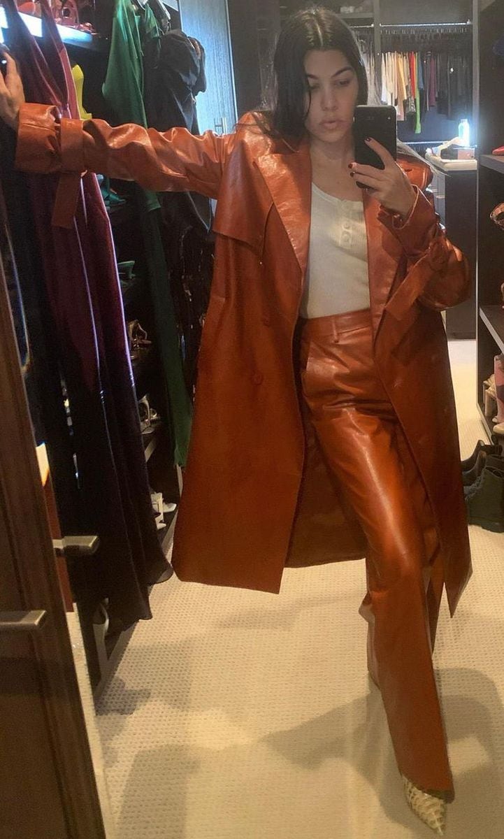 Kourtney Kardashian wearing a brown leather outfit with a mid-length coat and white top