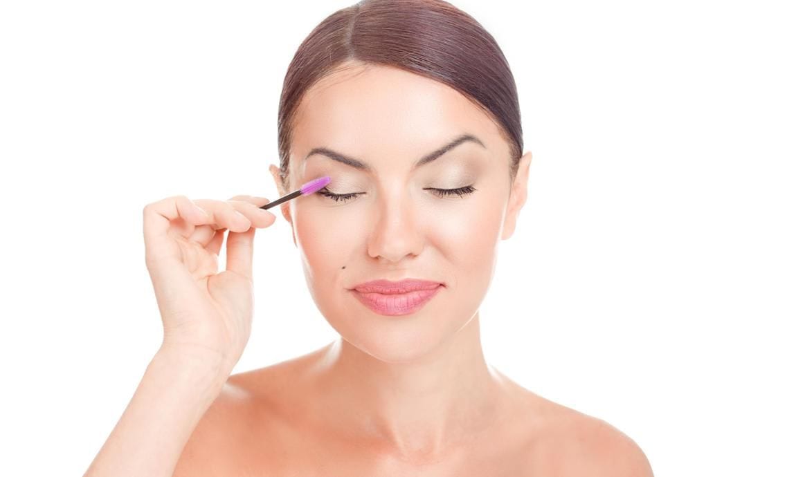 Woman applying oil to her eyelashes using a mascara wand