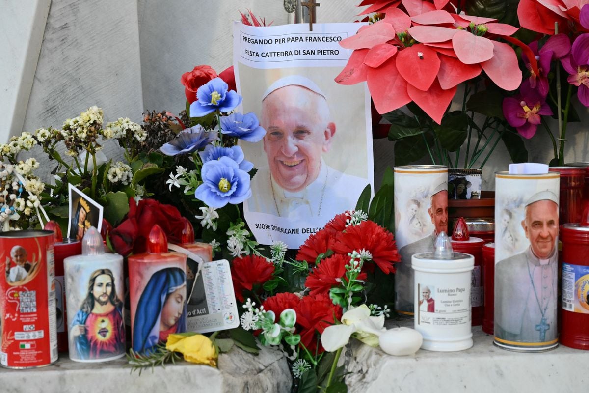 Candles, flowers and a portrait of Pope Francis are laid at the statue of John Paul II outside the Gemelli hospital where Pope Francis is hospitalized in Rome on February 22, 2025. Pope Francis passes another calm night in hospital, the Vatican said on February 21, 2025 in its morning update, as the 88-year-old spent his seventh day in hospital being treated for pneumonia. 