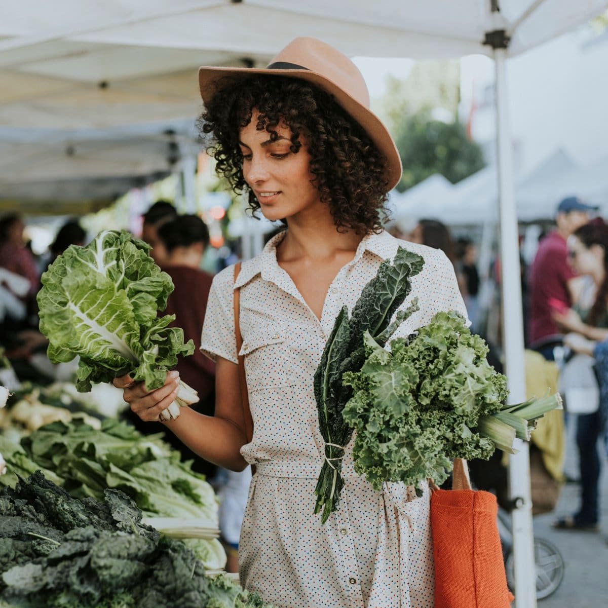 Beautiful woman buying kale at a farmers market