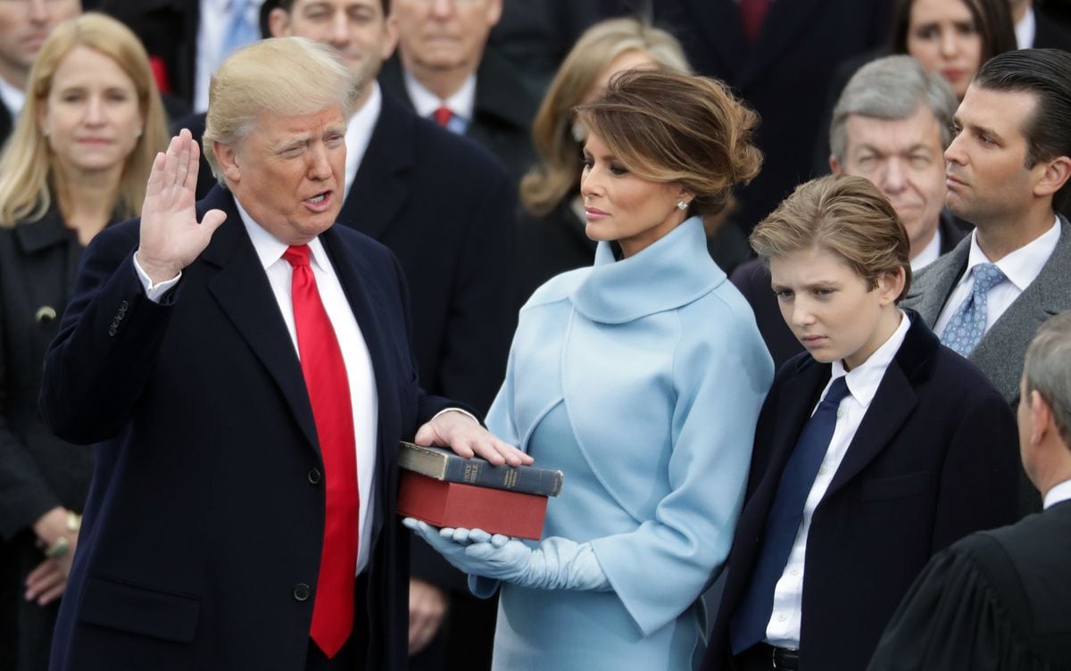 President Donald Trump takes the oath of office as his wife Melania Trump holds the bible 