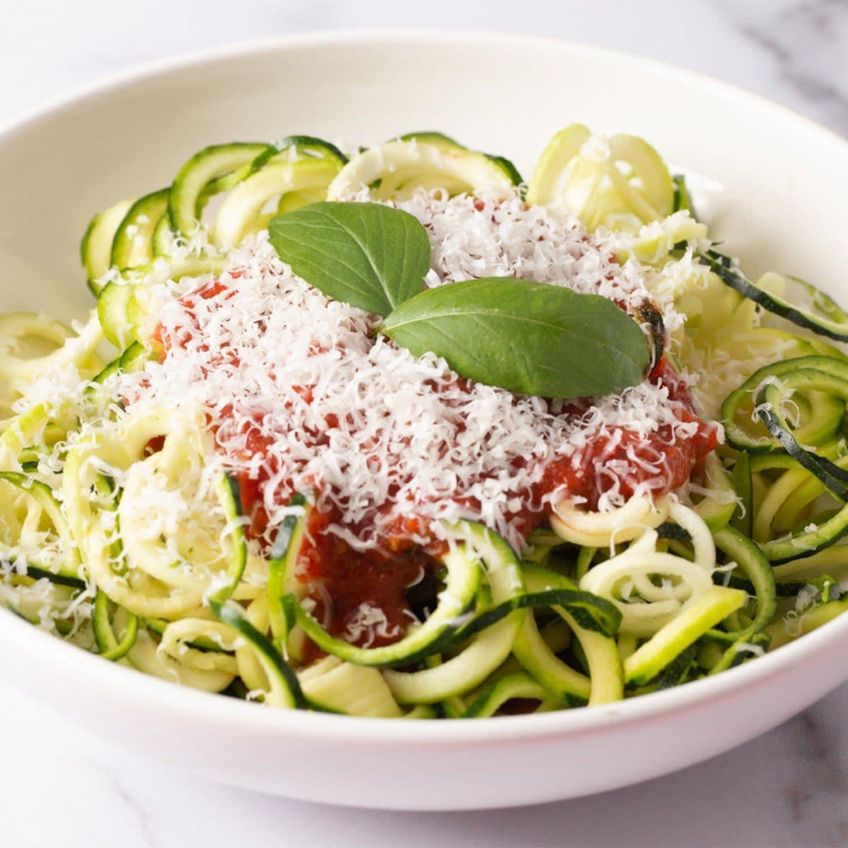 Zucchini Pasta Topped with Parmesean Cheese and Tomato Sauce