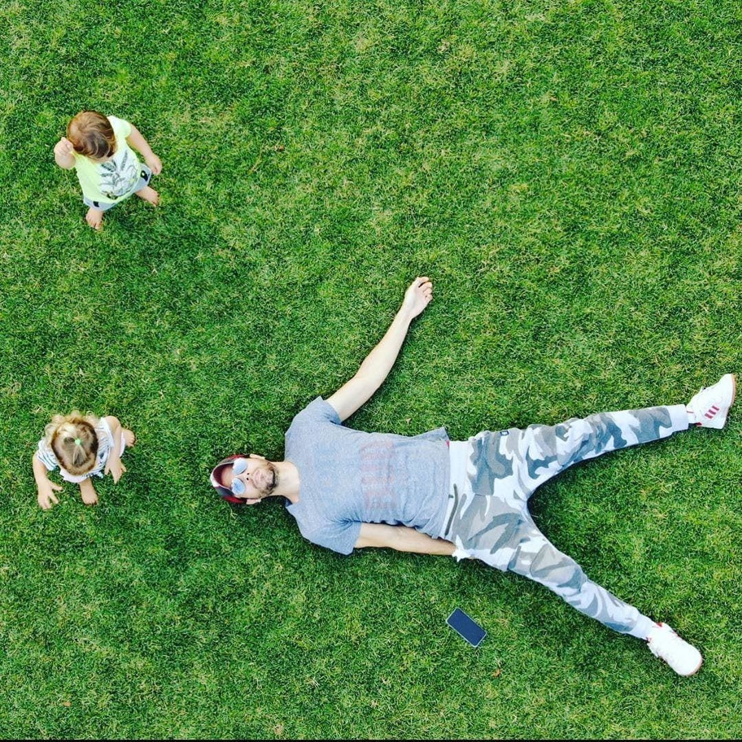 Enrique Iglesias lays on the grass while twins play