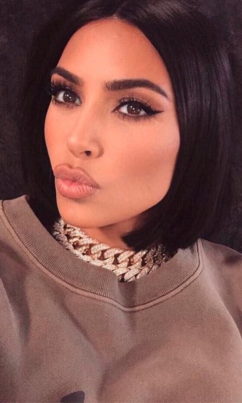 Kim Kardashian with a large shiny chain and athletic sweatshirt
