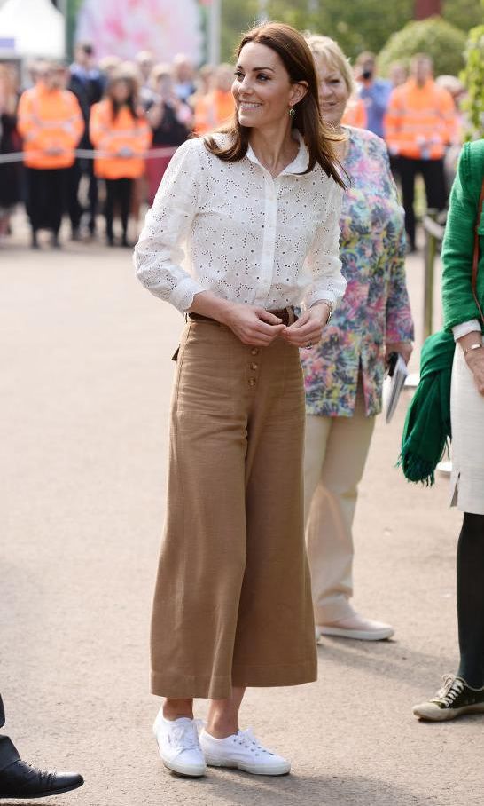 Kate Middleton wearing white sneakers by Superga, wide-leg pants, and a blouse