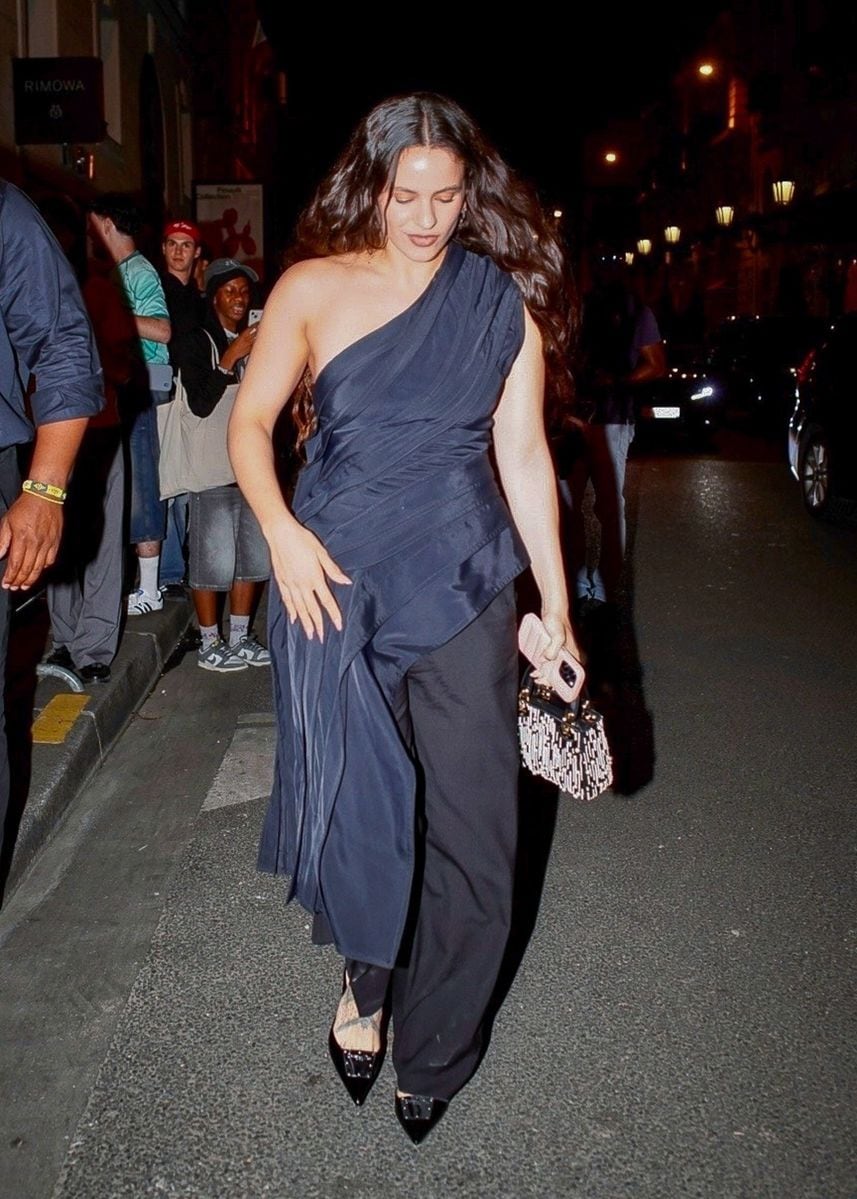 Singer Rosalia stuns in a shoulder-less black dress as she warmly greets fans after a Dior party in Paris.
