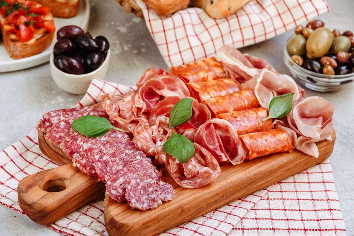 Antipasto of prosciutto, ham, and salami are paired with olives, tomato, and basil bruschetta.