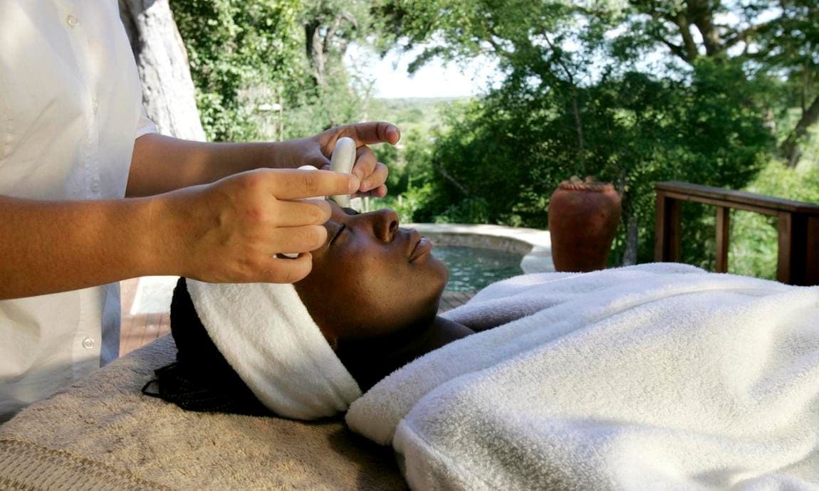 Woman having hot stone therapy done on her face