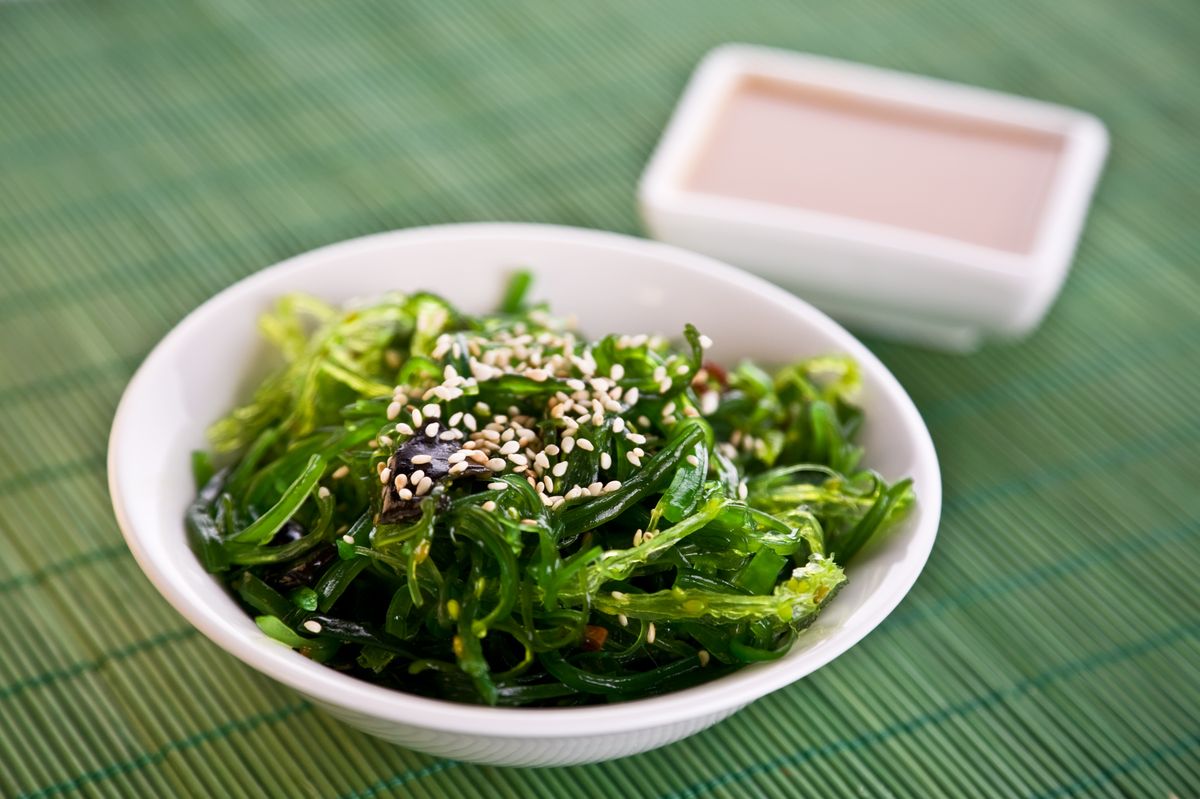 Wakame seaweed salad with nut sauce, garnished with sesame seeds and red chili pepper 