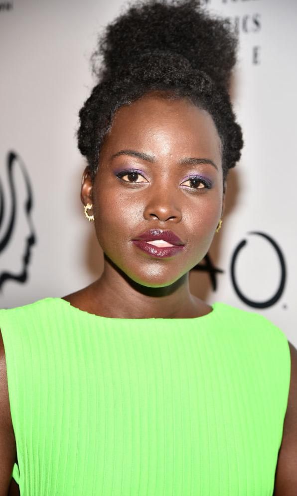 Lupita Nyong'o wearing a neon green dress and a dark lip colorn