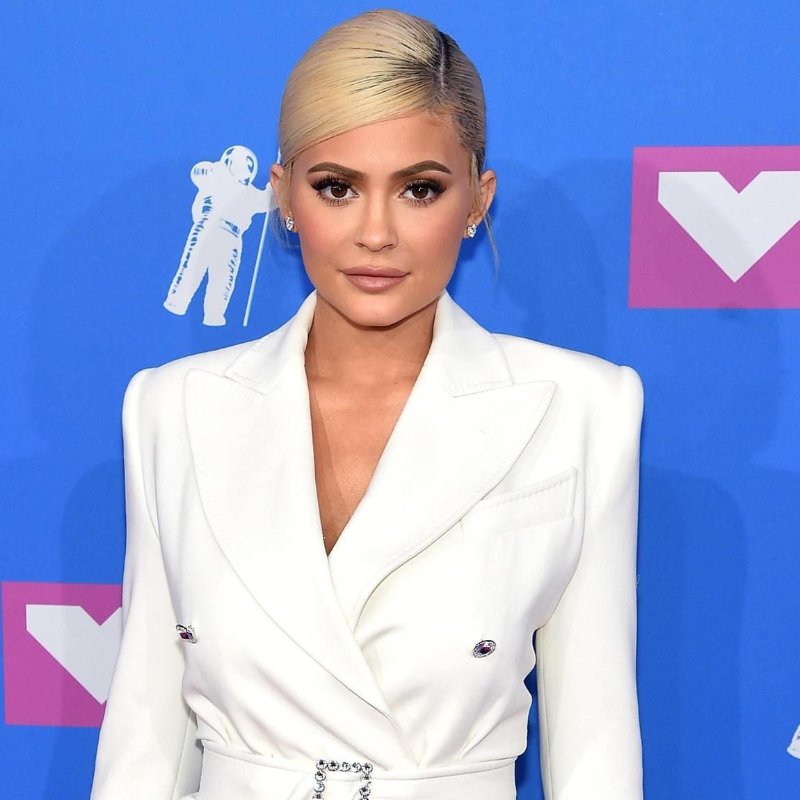 Kylie Jenner in a white suit with blonde hair in an up-do with a side part