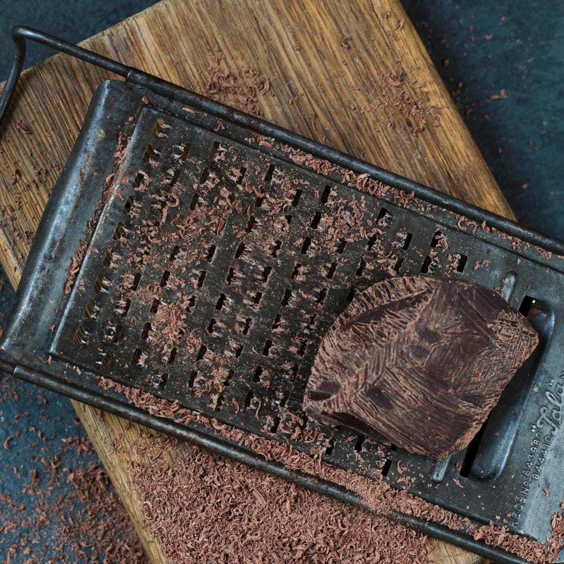 Grated dark chocolate with grater and piece of chocolate