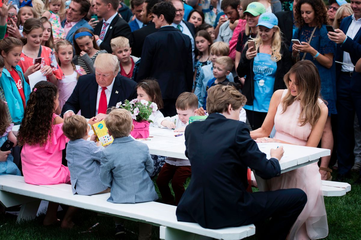 US President Donald Trump, Barron Trump(R) and US First Lady Melania Trump join others to write notes to service members during the Easter Egg Roll on the South Lawn of the White House April 17, 2017 in Washington, DC. / AFP PHOTO / Brendan Smialowski        (Photo credit should read BRENDAN SMIALOWSKI/AFP via Getty Images)