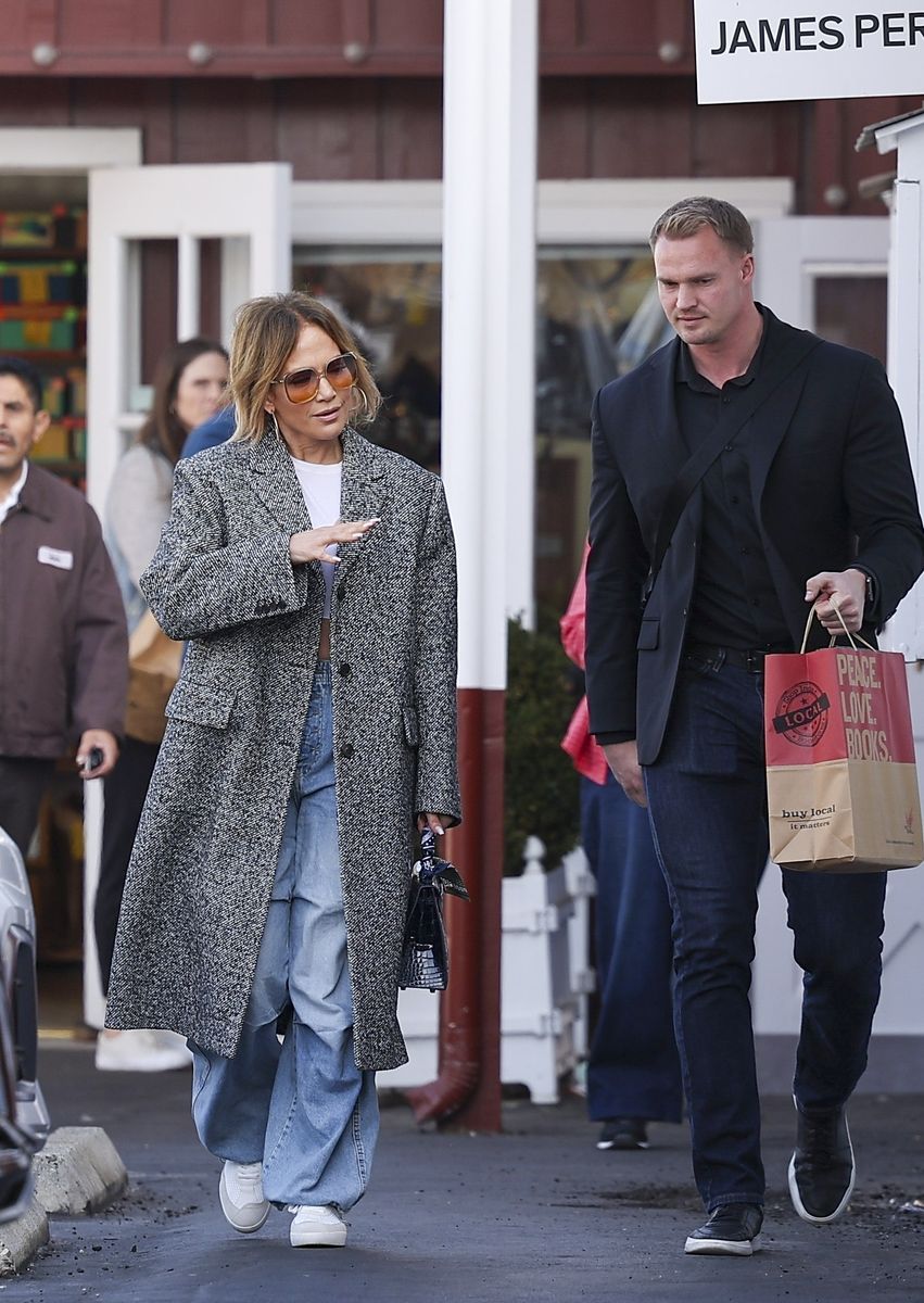 Jennifer Lopez flashes a smile after finishing some holiday shopping at the Brentwood Country Mart. Her assistant and a dashing bodyguard joined her as she browsed for festive finds.