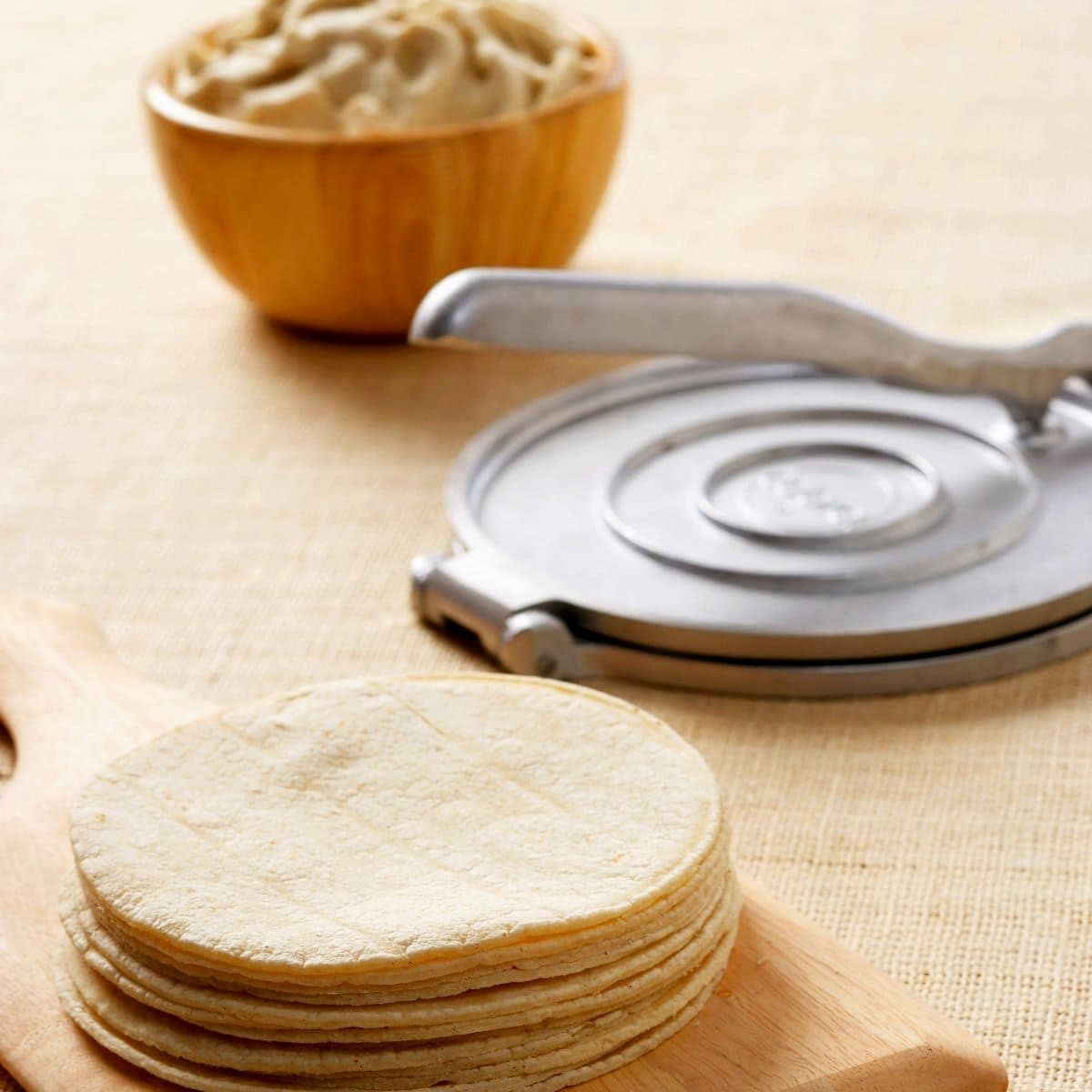 Stack of Freshly Made Tortillas with a Tortilla Press and Bowl of Batter