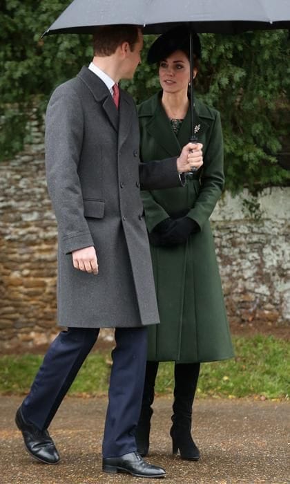 Kate Middleton with green coat holding a black umbrella next to Prince william