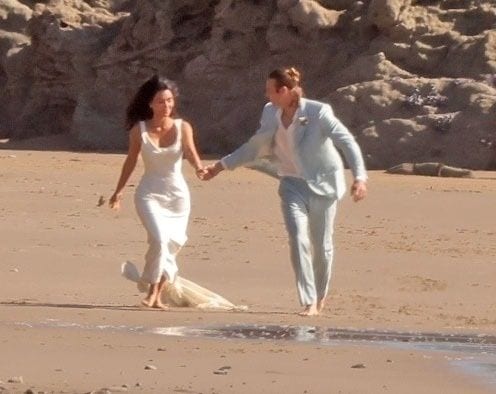 Kim Kardashian gets married on the TV show "All's Fair" set on the Malibu beach. Kim and her TV groom, Matthew Noszka, ran down the beach as he picked her up, and they splashed in the water.