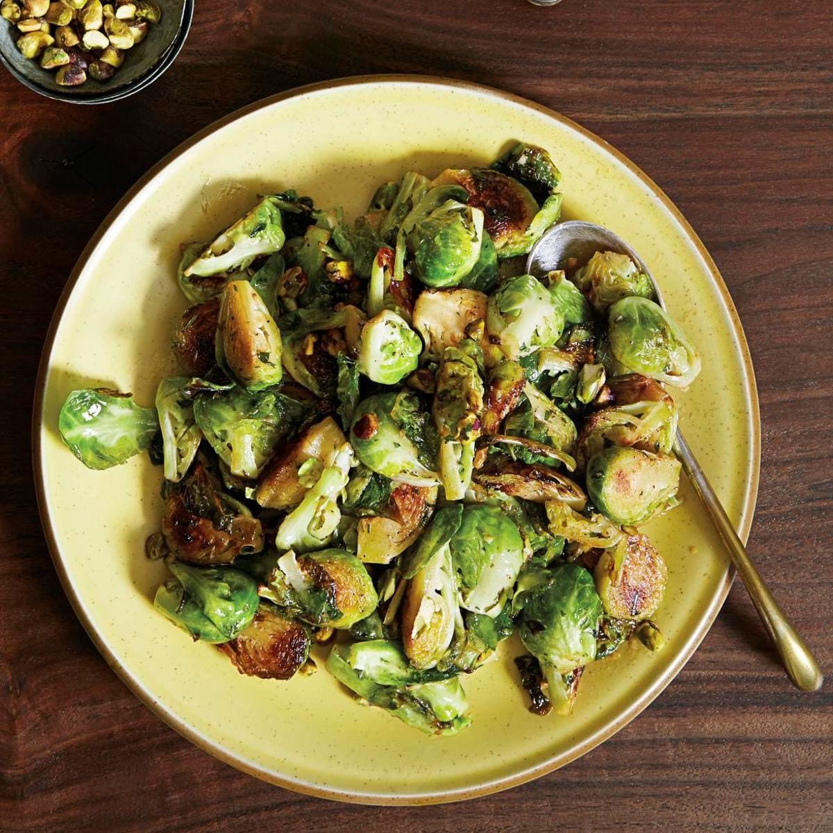 elegant dinner table with roasted Brussel sprouts, pistachios, and wine