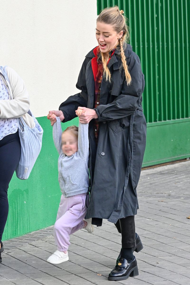  Amber Heard smiles as she takes her daughter Oonagh Paige shopping for treats in Madrid, Spain. The 'Aquaman' star, 37, and the cute tot were spotted at an American grocery store where they bought candy. Heard looked stylish for the outing, wearing her long hair in braids and pairing chunky heeled loafers with skinny leather pants and a plaid shirt, topping off with a red blazer and black overcoat. She looked happy and relaxed as she swung her two-year-old as they walked.