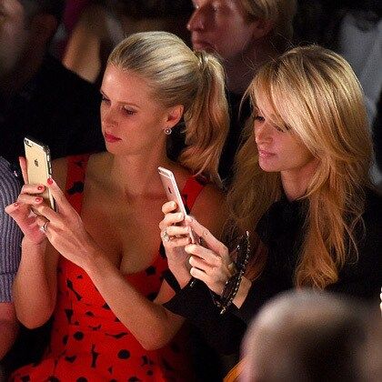 Sisters Nicky and Paris Hilton snapped images on their iPhones from the front row of the Jeremy Scott fashion show.
Photo: Nicholas Hunt/Getty Images for New York Fashion Week: The Shows