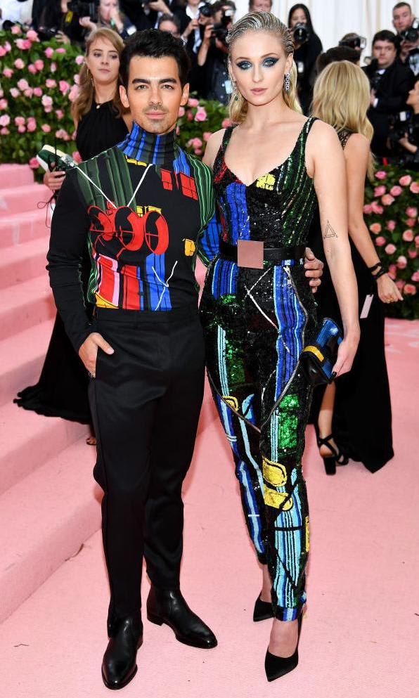 Sophie Turner in a brightly-colored jumpsuit and Joe Jonas in a brightly colored top and black pants