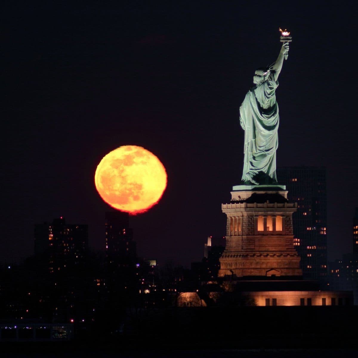 Full Snow Moon Rises Behind the Statue of Liberty in New York City