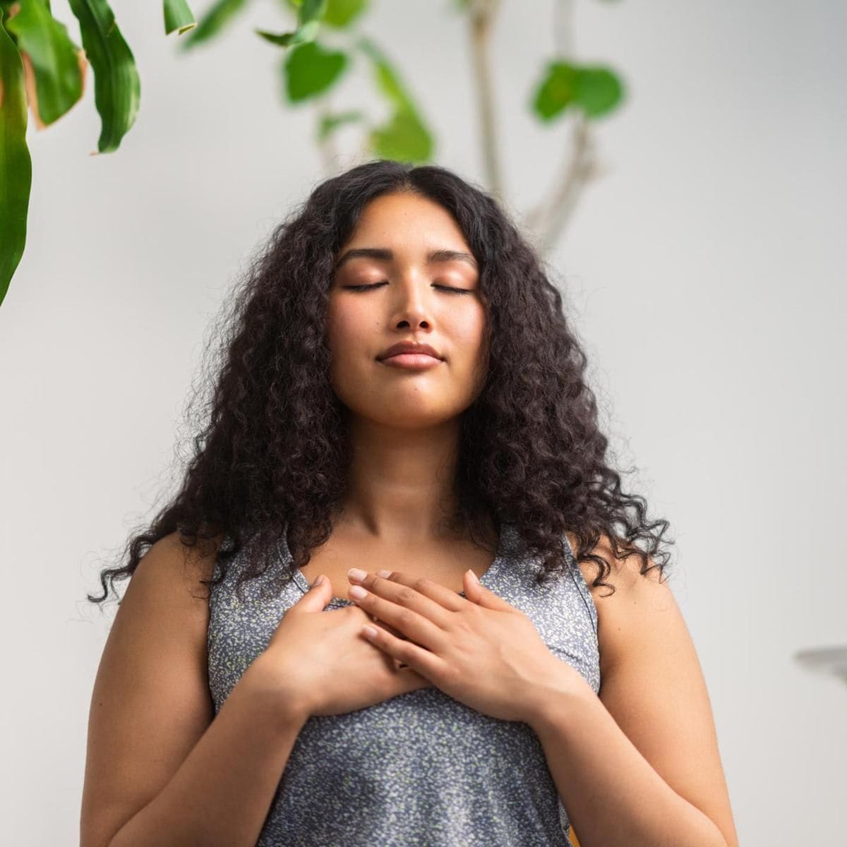 A beautiful and young multiracial woman is doing breathing exercise at home.