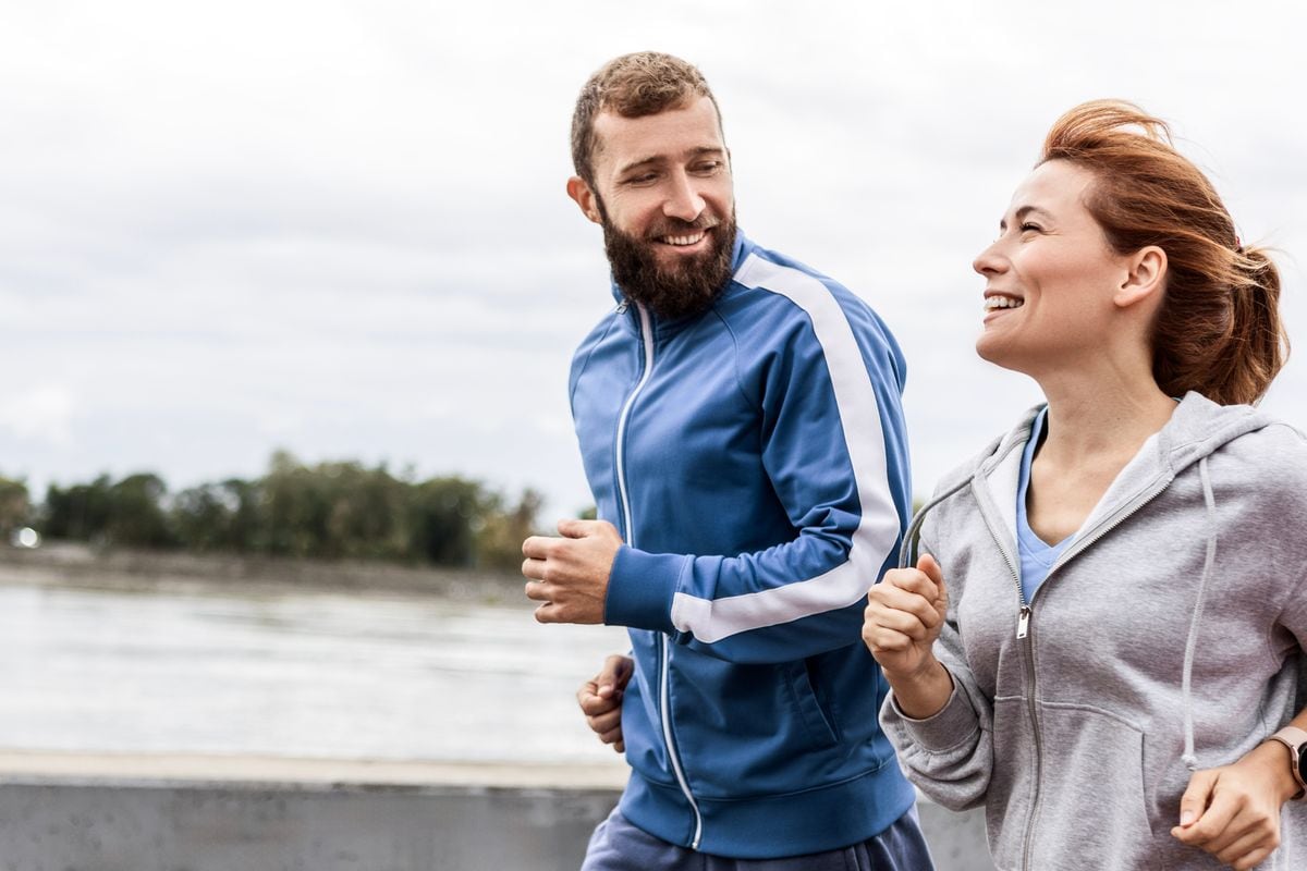 Pareja alegre corriendo juntos al aire libre