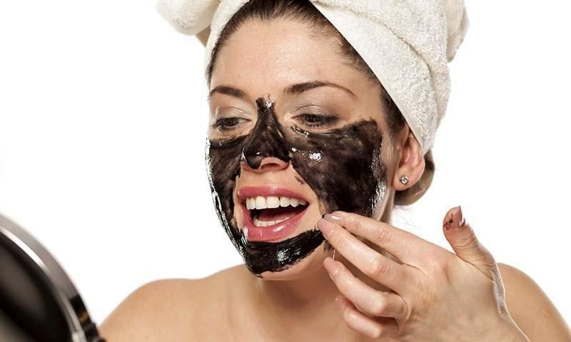 Woman applying charcoal mask