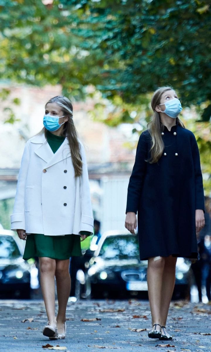 Queen Letizia's daughters bundled up in chic outerwear during their visit to the La Vega Weapons Factory ahead of the 2020 Princess of Asturias Awards in Oviedo. The sisters both turned to designs from Carolina Herrera with Sofia recycling a navy coat and Leonor pairing her white jacket from the designer with a green Mango dress.