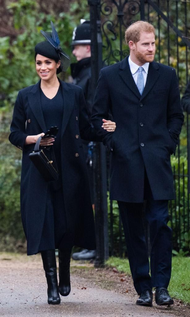 Meghan Markle con vestido y abrigo azul marino y botas altas de Victoria Beckham