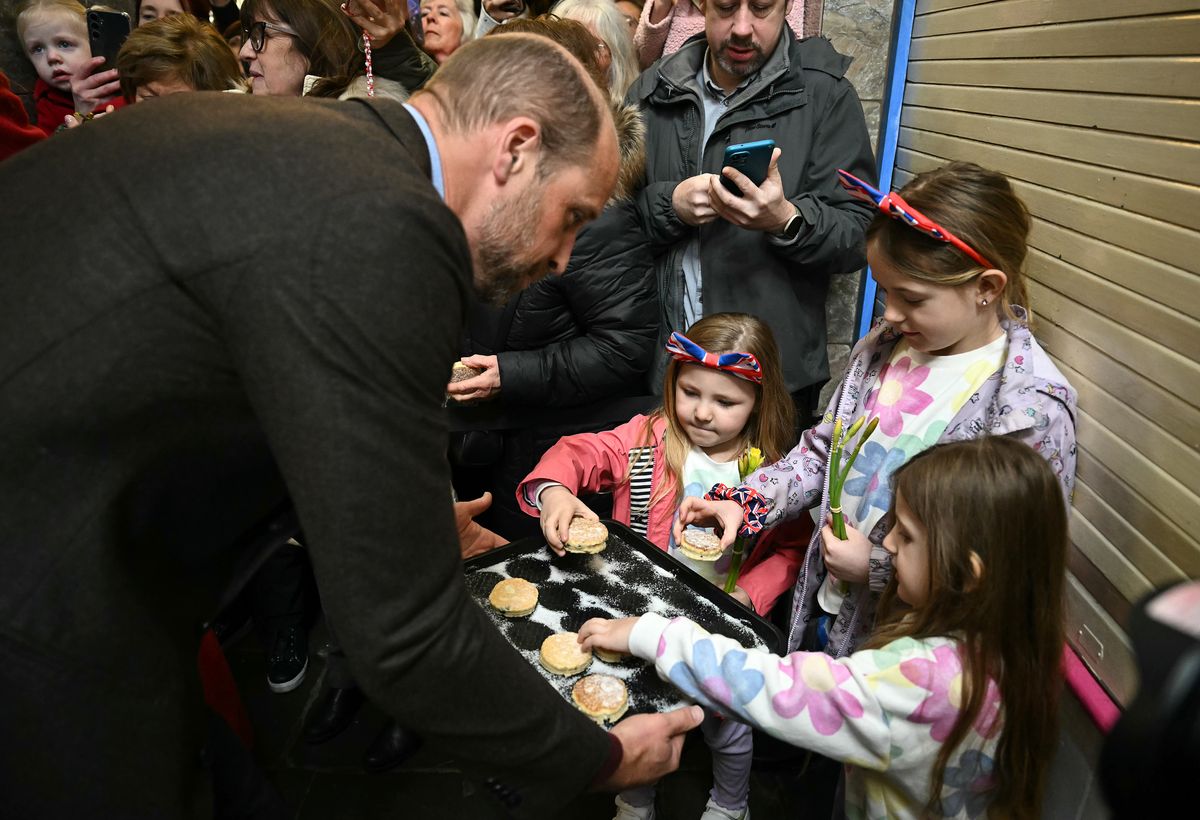 PONTYPRIDD, WALES - FEBRUARY 26: Prince William, Prince of Wales distributes to well-wishers the Welsh Cakes made by himself and Catherine, Princess of Wales, during a visit to Pontypridd Market on February 26, 2025 in Pontypridd, Wales. In December 2024, Pontypridd was one of a number of towns across Wales which was hit by severe flooding as a result of Storm Bert and Storm Darragh. The Prince and Princess met with local residents, learning about their experiences and the impact of recent events in the town. (Photo by Ben Stansall - WPA Pool/Getty Images)