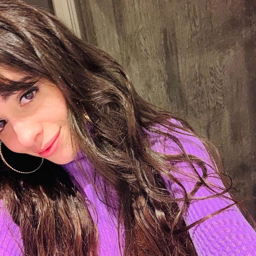 Camila Cabello con hoop earrings y sueter morado