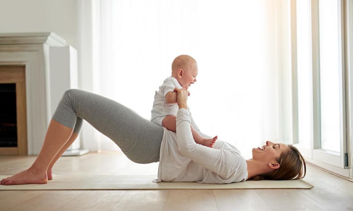 Woman does a bridge exercise with her baby