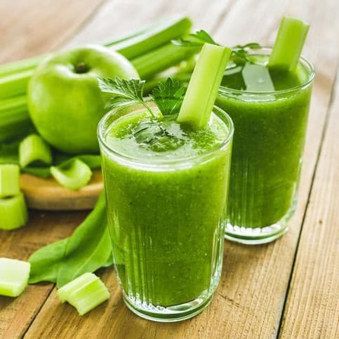 Green juice made of apples, spinach, and celery