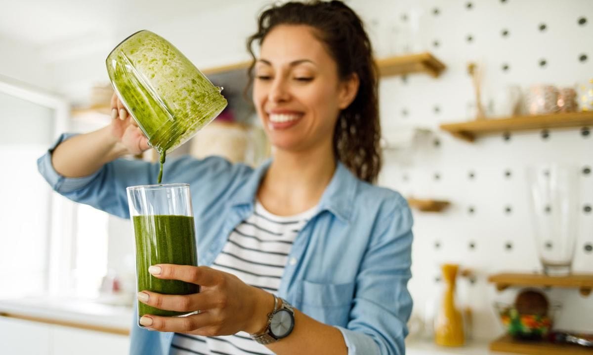 Young woman preparing a green smoothie at home