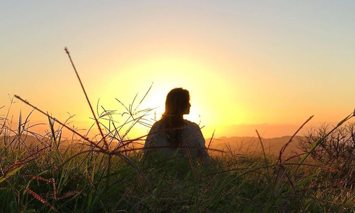 Gisele Bündchen posing in the grass at sunset.