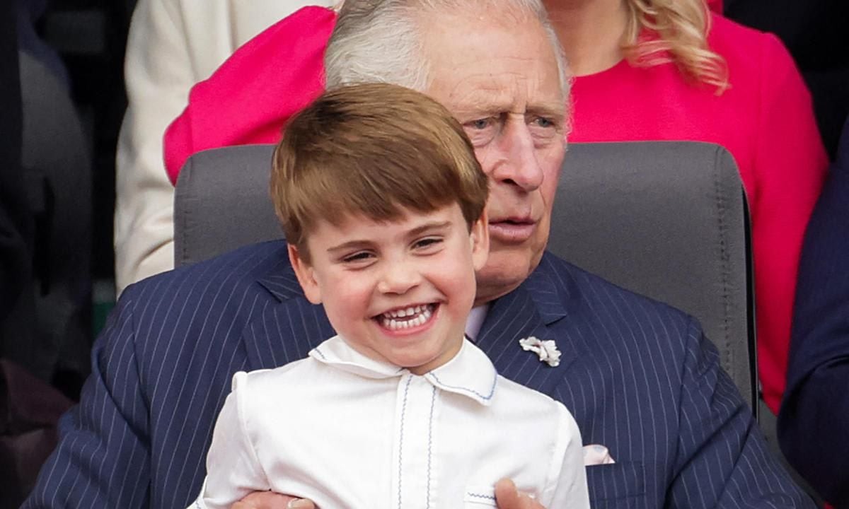 Louis was all smiles sitting on his grandfather Prince Charles' lap.