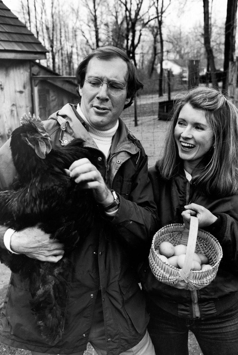  Andy Stewart holding a black Cochin hen as Martha holds a basket of eggs in the barnyard of their home (1980)