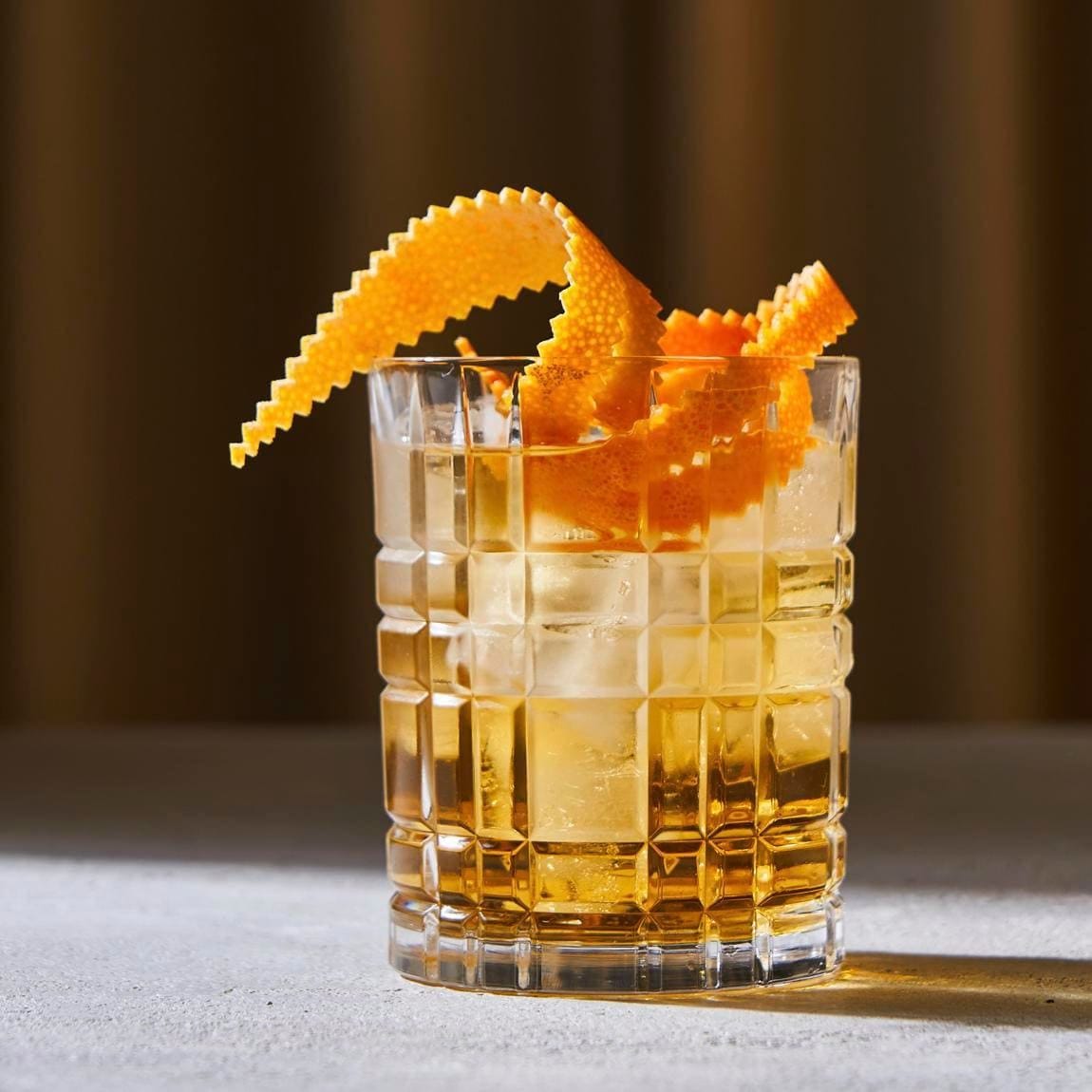 Glass cup with cold old fashioned cocktail with whiskey and orange peel