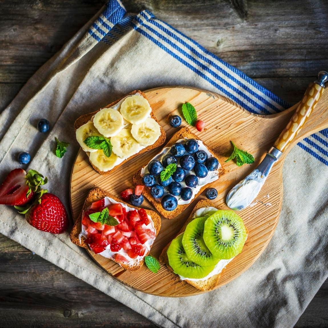 Healthy fruit open sandwiches on a wooden board