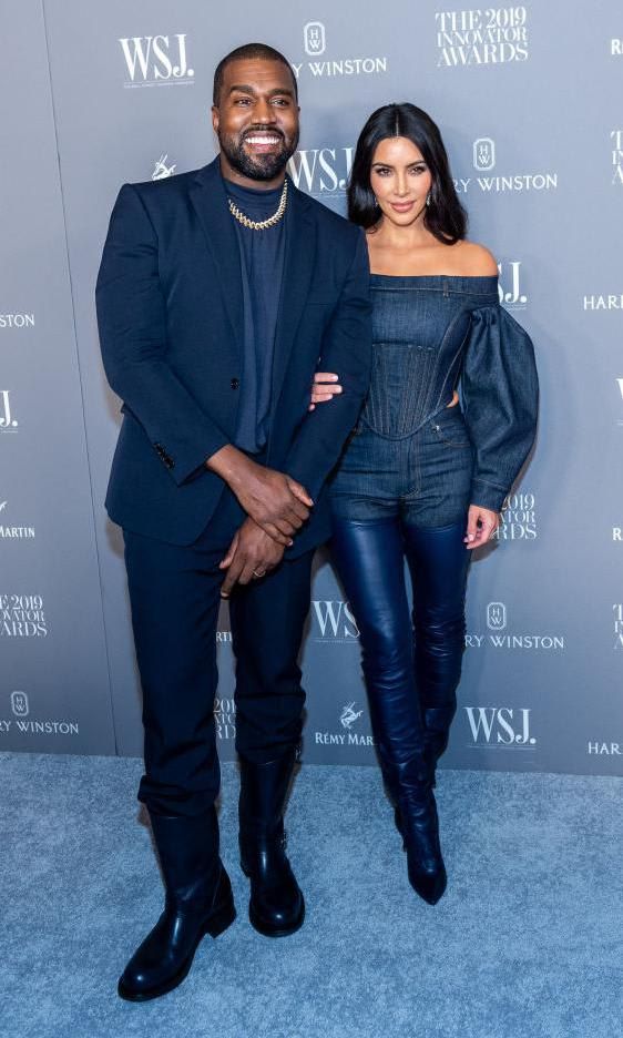 Kanye West in a blue suit and Kim Kardashian in a denim outfit with high boots