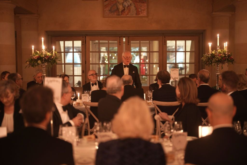 A distinguished guest delivers a speech at a candlelit gala dinner at Highgrove House, attended by elegantly dressed guests.