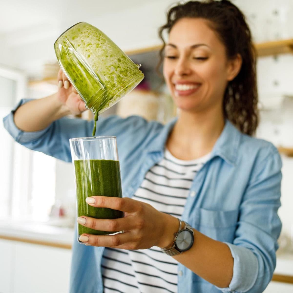 Young woman preparing a green smoothie at home