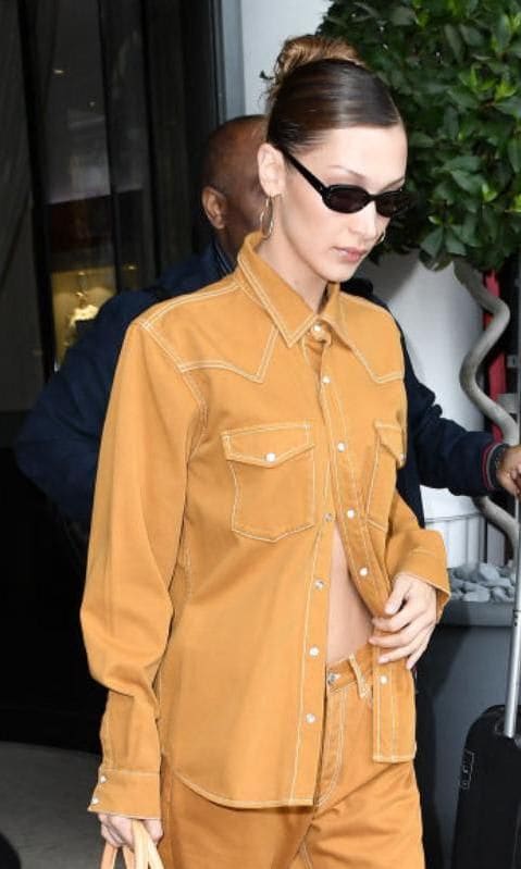 Bella Hadid con rosca alta y raya al medio con lentes oscuros y atuendo caramel