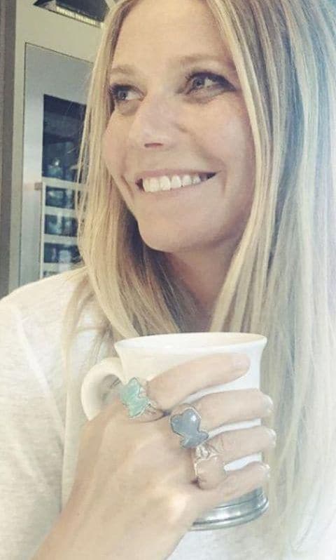 Gwyneth Paltrow with loose hair and a white t shirt drinking from a cup