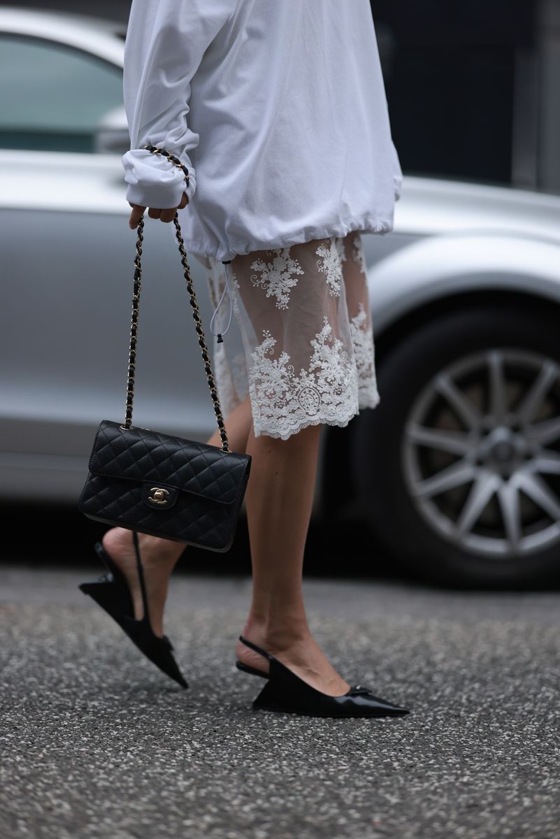 Anna Winter was seen on May 22, 2024, in Hamburg, Germany, wearing a Beams white cotton oversized sweater, a Source Unknown white laced midi skirt, a Chanel black leather classic bag, and Prada black shiny leather logo heels. 
