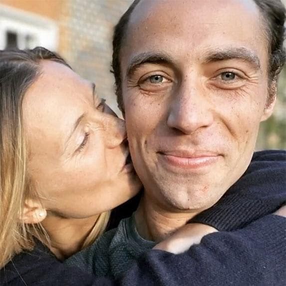 James Middleton posing, beardless, with fiance kissing his cheek